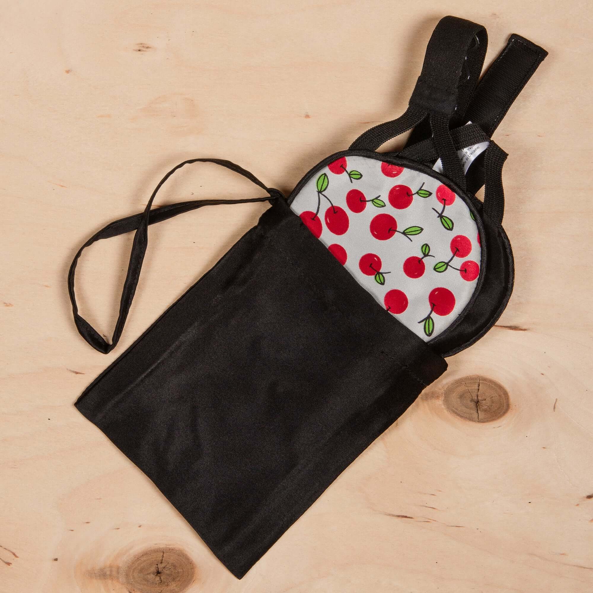 Black silk storage case with a sleep mask featuring a cherry pattern, ideal for travel and comfort.