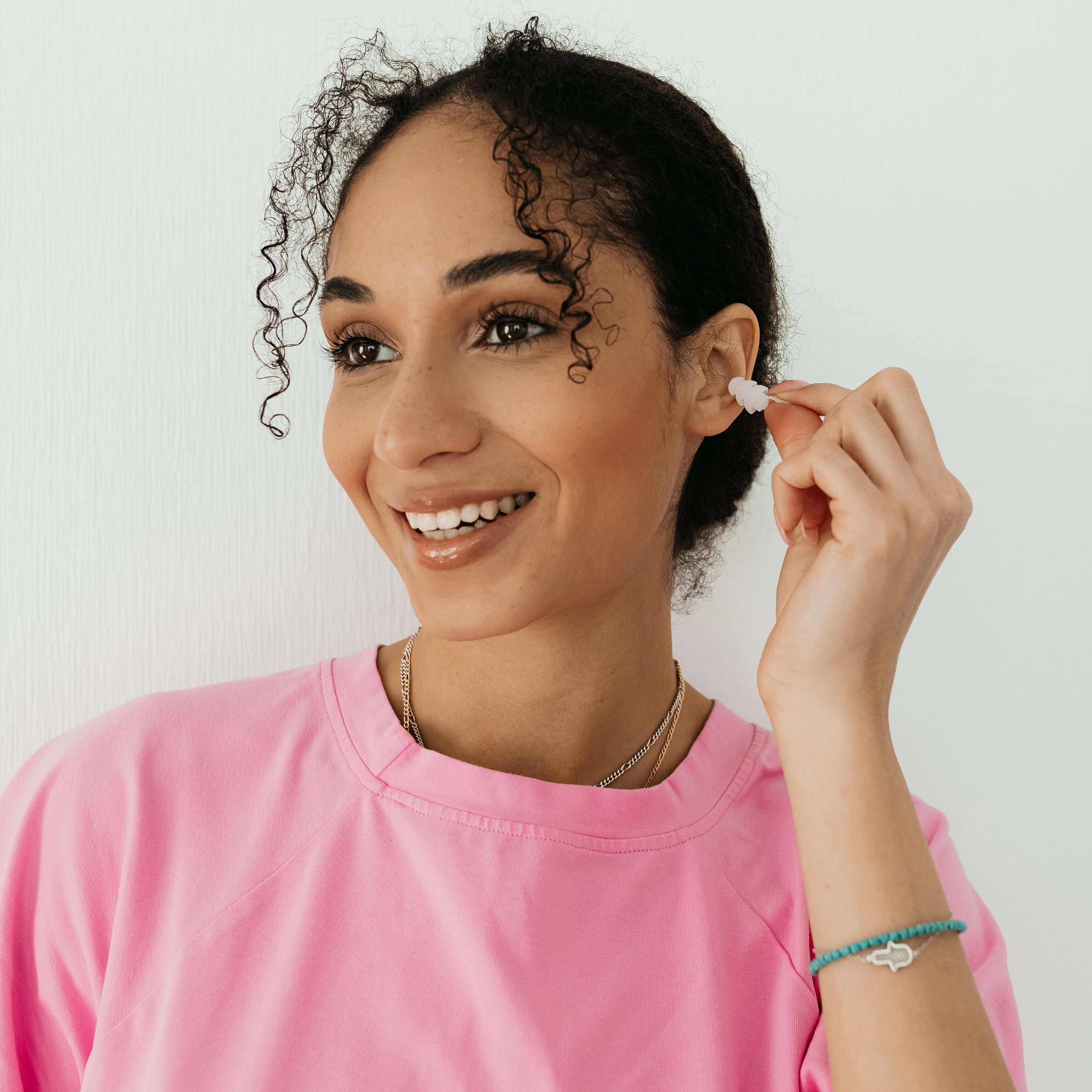 Woman wearing Kokon Universe noise-reducing earplugs, showcasing comfort and style, available in XS, S, M sizes.