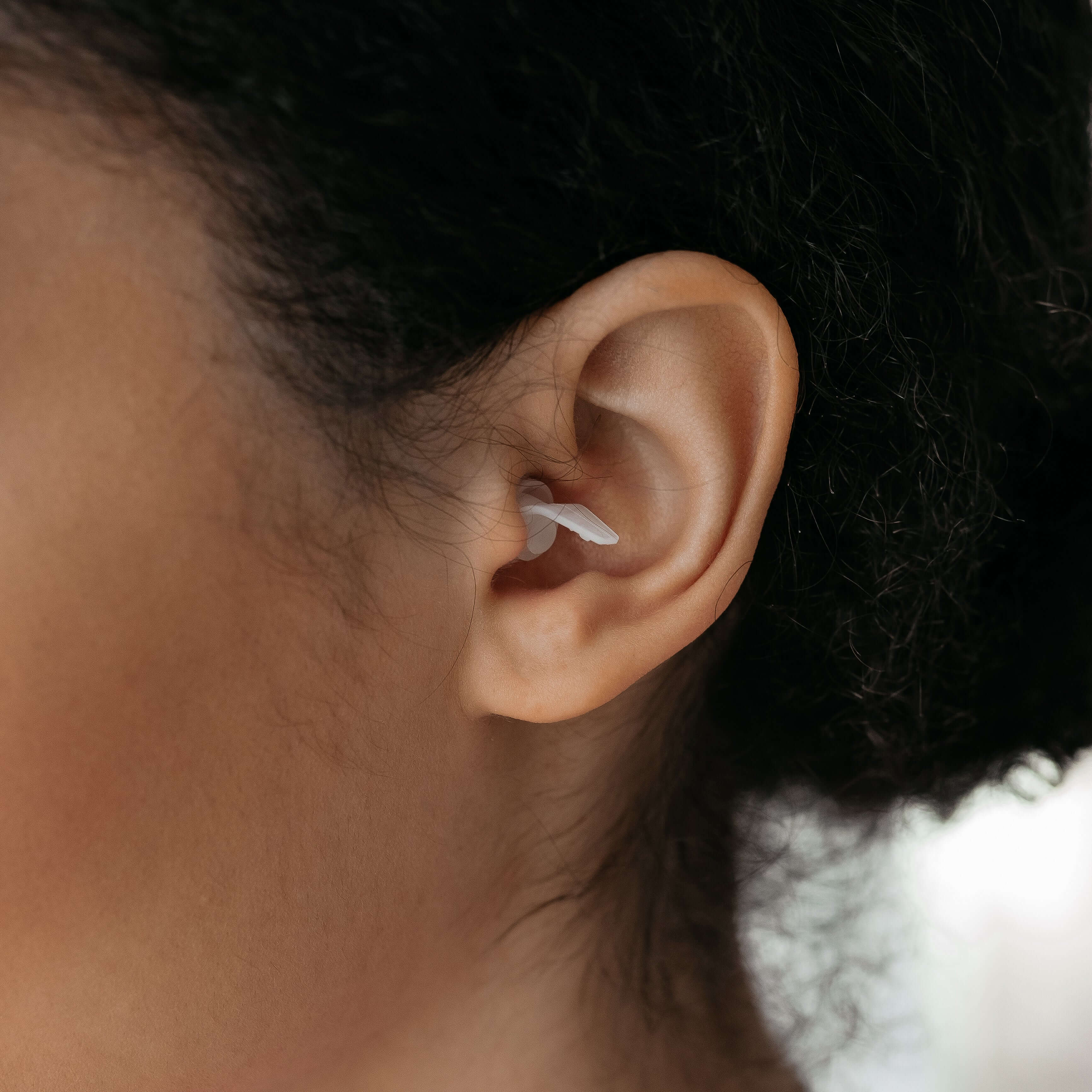 Close-up of a person wearing Kokon Universe noise reducing earplugs, showcasing soft silicone design fitting the outer ear.