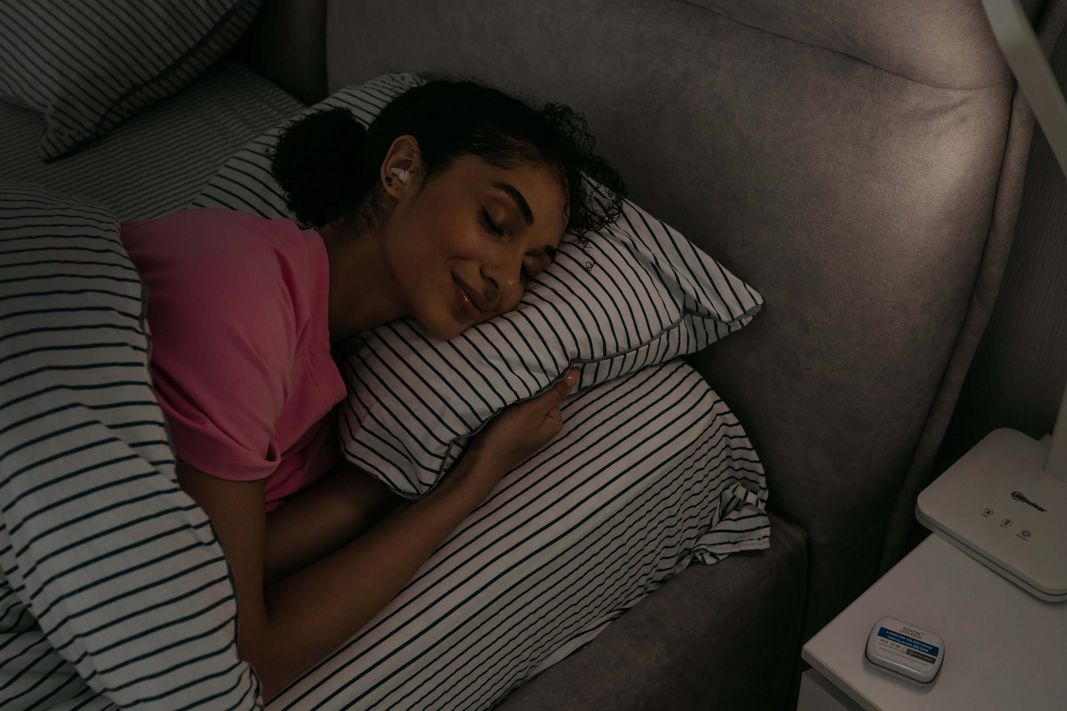 Woman peacefully sleeping on striped pillows, showcasing comfort and relaxation in her bedroom.