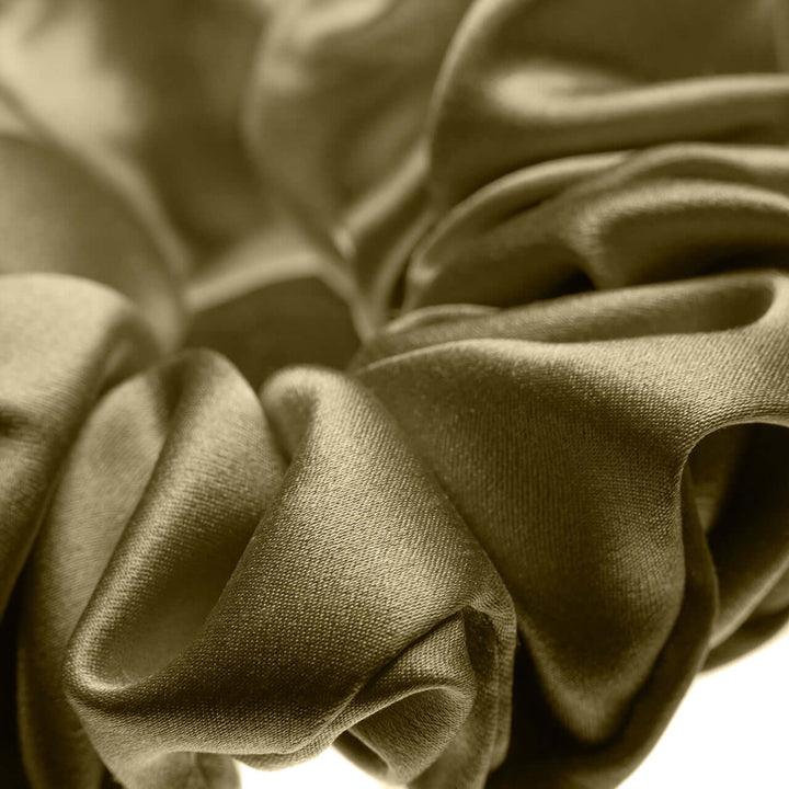 Close-up of a large pure Mulberry silk scrunchie in golden hue, showcasing its smooth texture and elasticity.