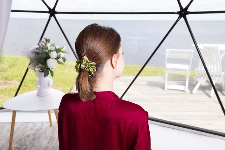 Woman wearing a large pure mulberry silk scrunchie in a ponytail, showcasing its smooth texture and durability.