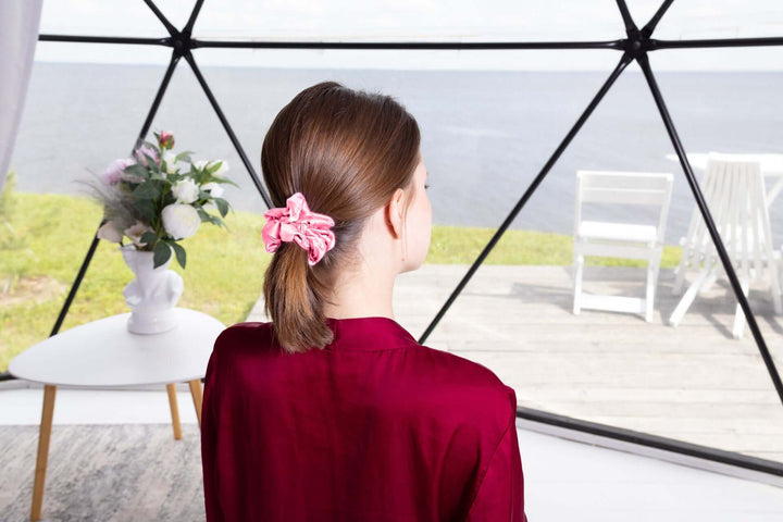 Model wearing a Pure Mulberry Silk Scrunchie in pink, showcasing its elegance and durability against a serene backdrop.