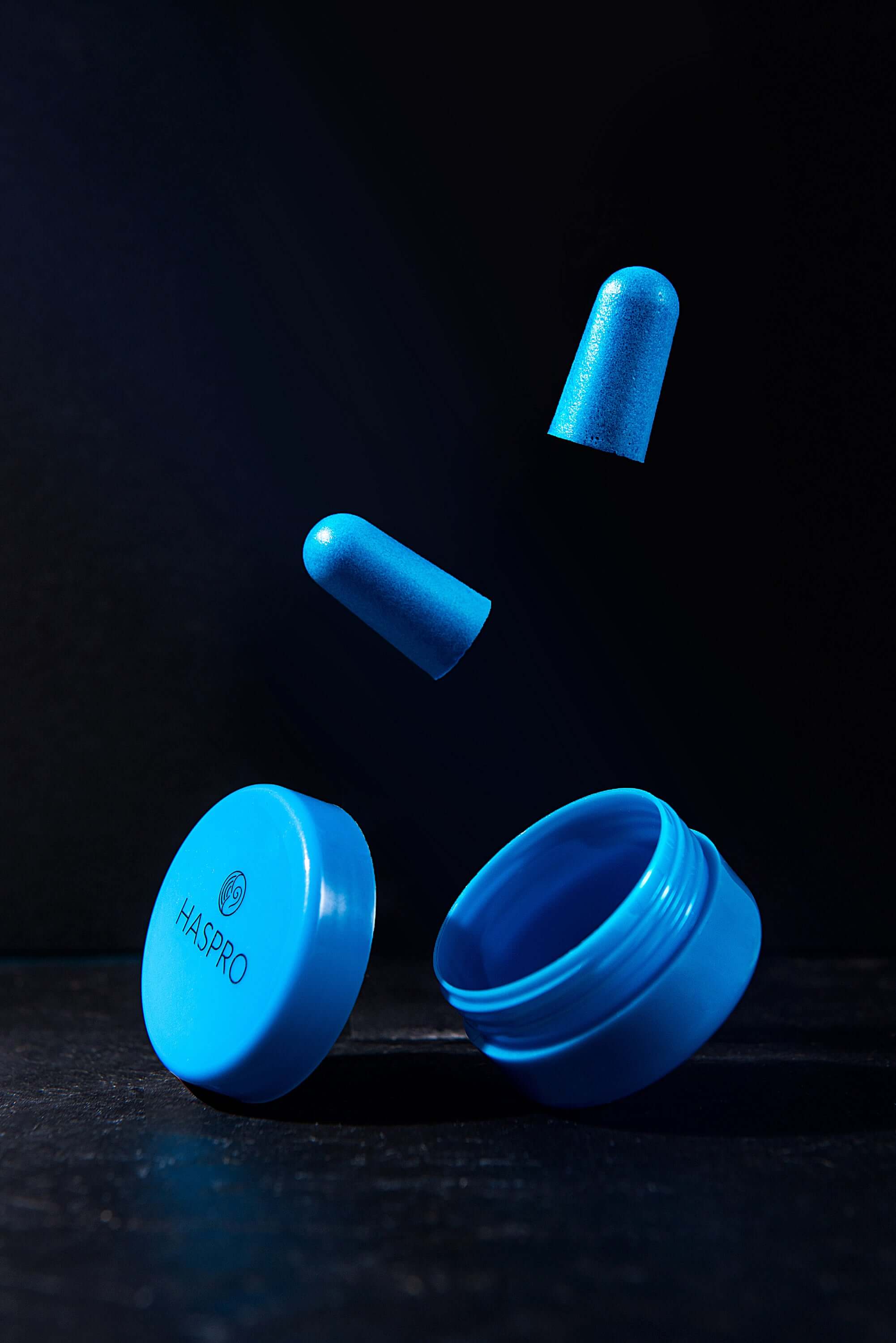 HASPRO blue earplug case with foam earplugs floating above, showcasing noise reduction features.