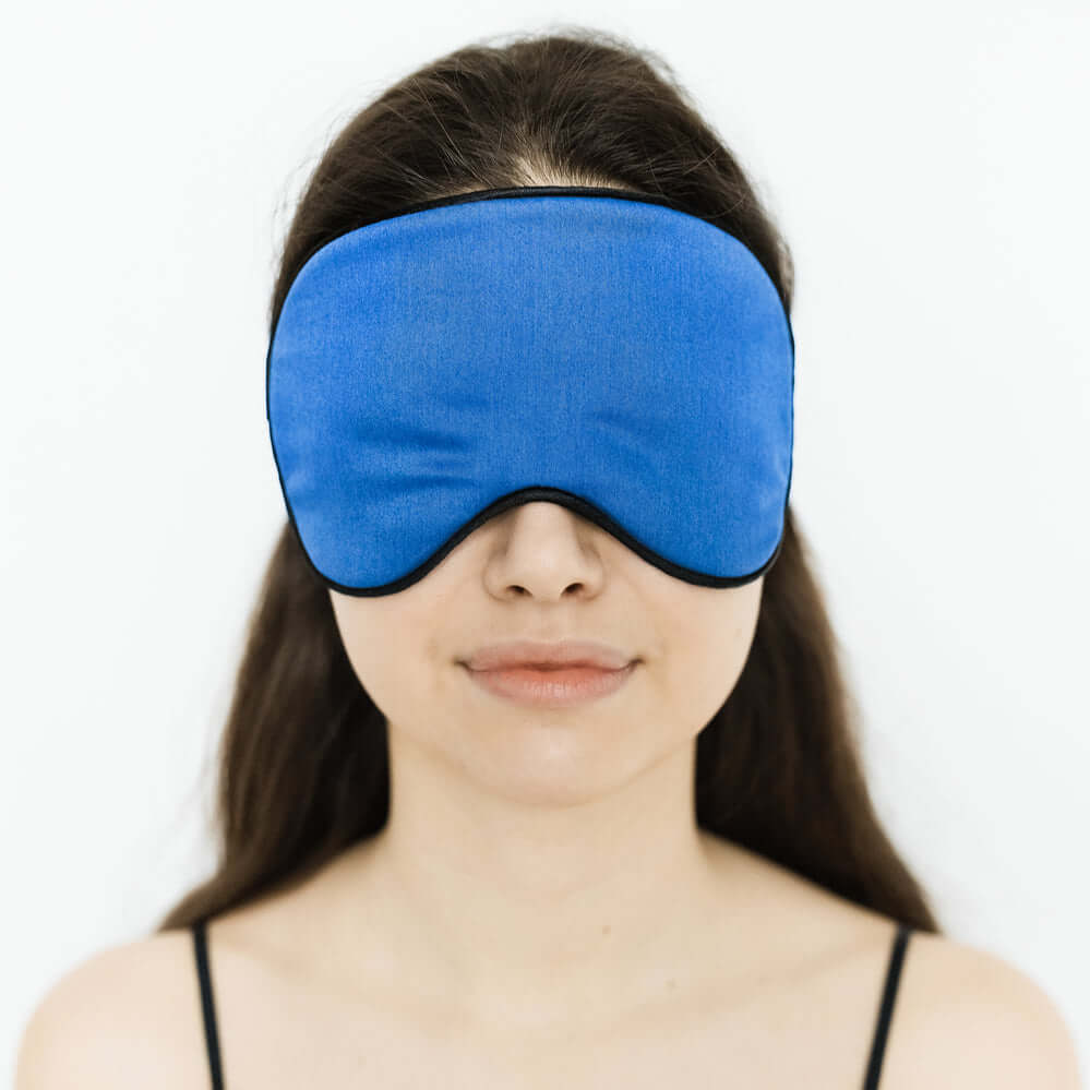Quietstore organic cotton sleep mask in blue worn by a woman, designed for comfort and light blockage.
