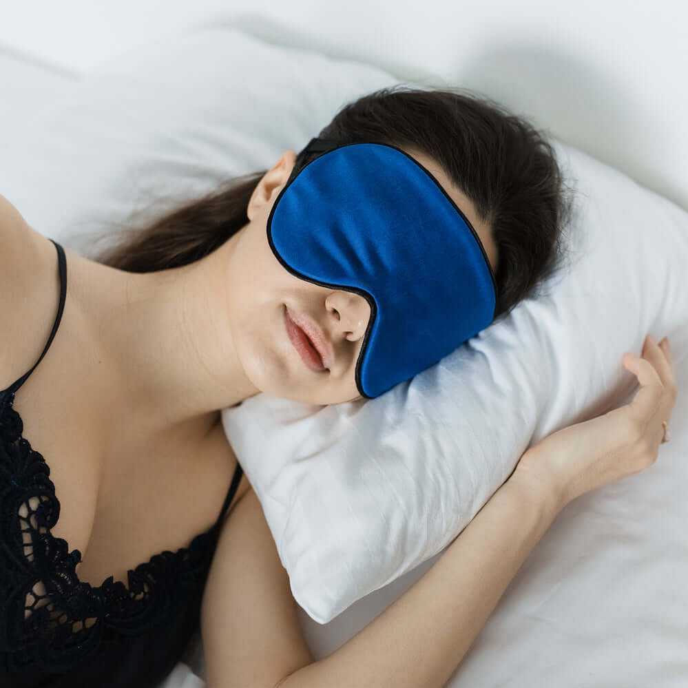 Woman wearing a blue non-slip sleep mask, resting peacefully on a pillow for improved REM sleep.