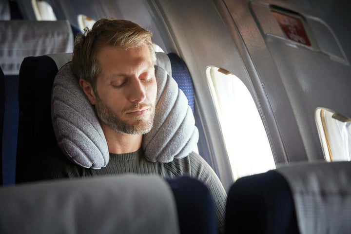 Man resting on airplane with inflatable travel neck pillow for maximum comfort during flights.