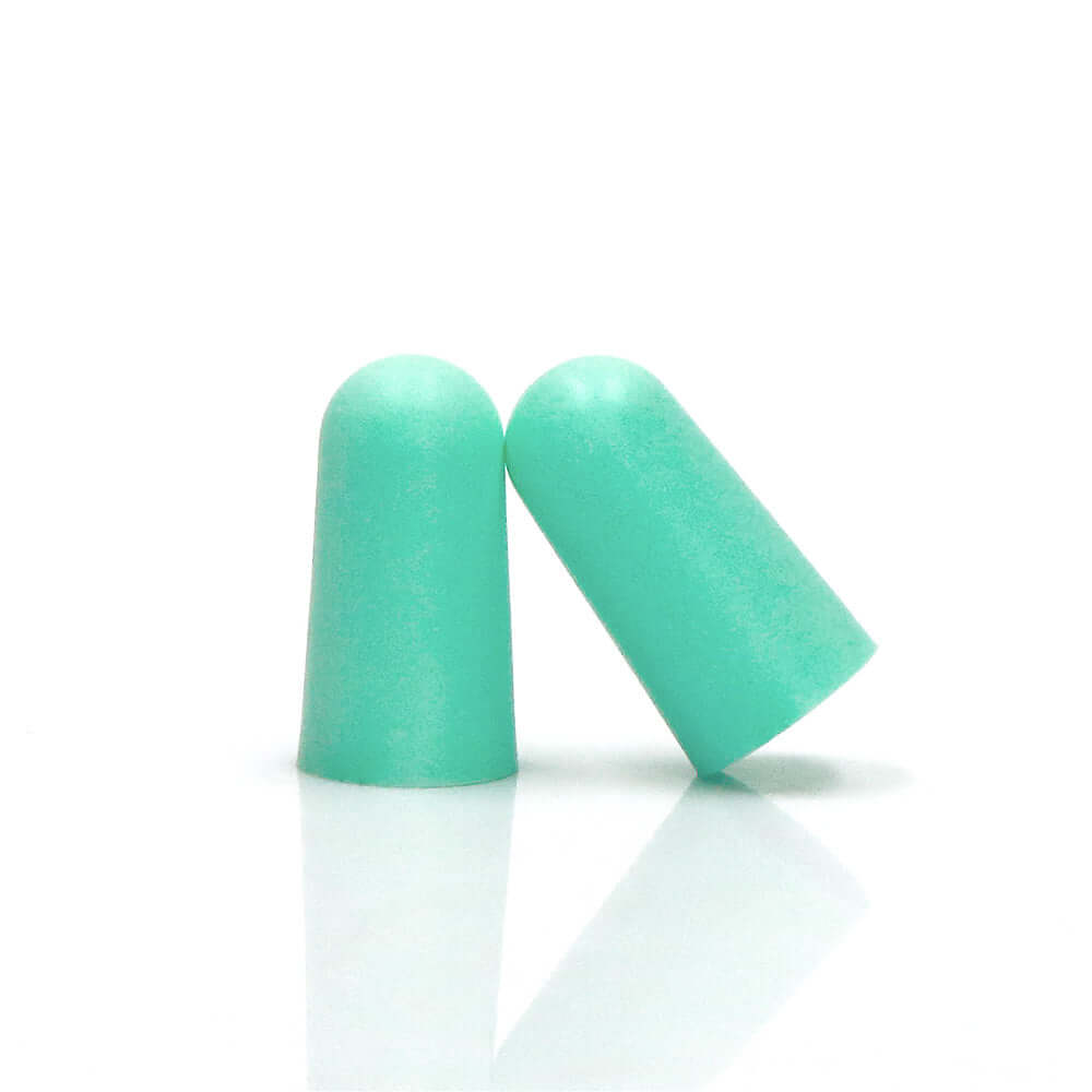 Two mint green foam sleeping earplugs on a reflective surface for high noise reduction and comfort.
