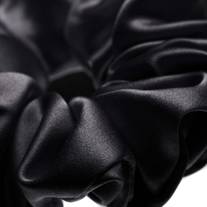 Close-up of a black pure Mulberry silk scrunchie, showcasing its smooth texture and luxurious shine.