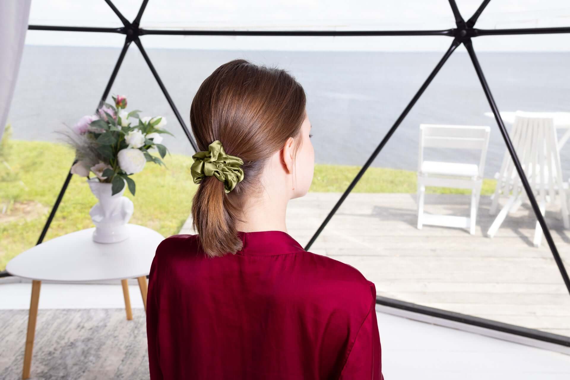 Woman wearing a large pure mulberry silk scrunchie in a ponytail, showcasing its smooth texture and durability.