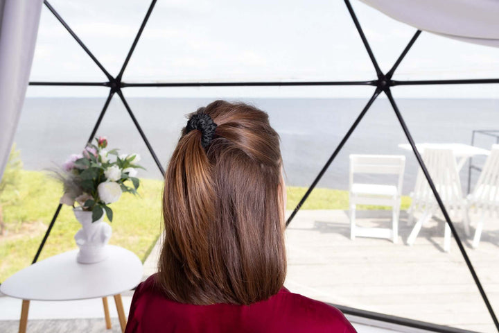 Woman with brown hair styled in a ponytail using a pure mulberry silk scrunchie, overlooking a scenic view.