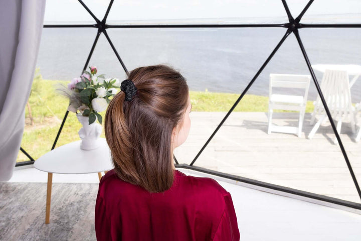 Woman wearing a Pure Mulberry Silk scrunchie, featuring a ponytail hairstyle, overlooking a scenic waterfront view.