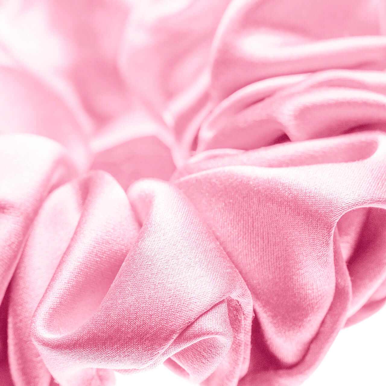 Close-up of a pure mulberry silk scrunchie in soft pink, showcasing smooth texture and durability.