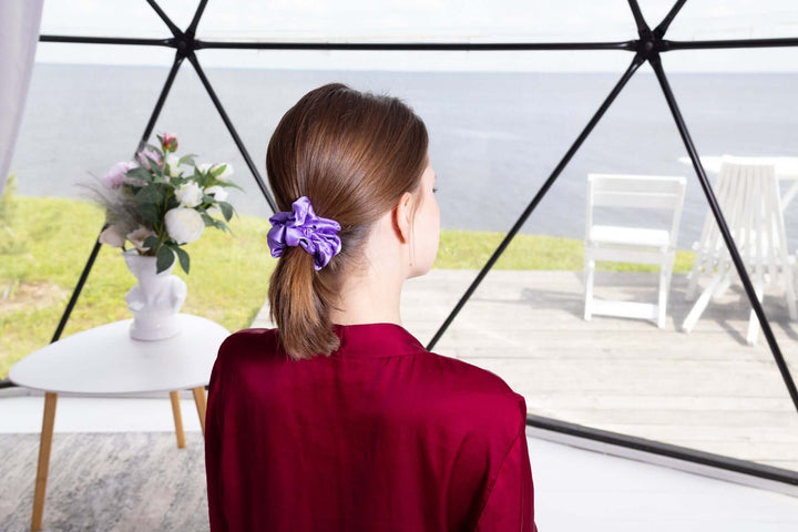 Woman wearing a pure mulberry silk scrunchie in a ponytail, showcasing elegance and comfort in a sleek interior setting.
