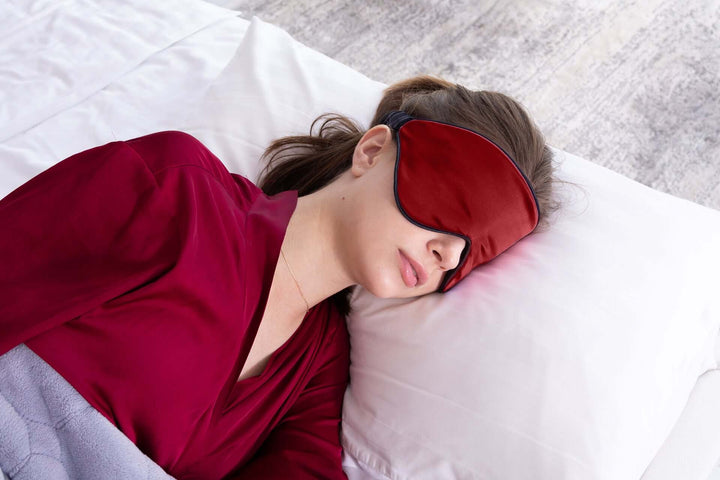 Woman sleeping peacefully with Quietstore 3.0 non-slip silk sleep mask on a bed.