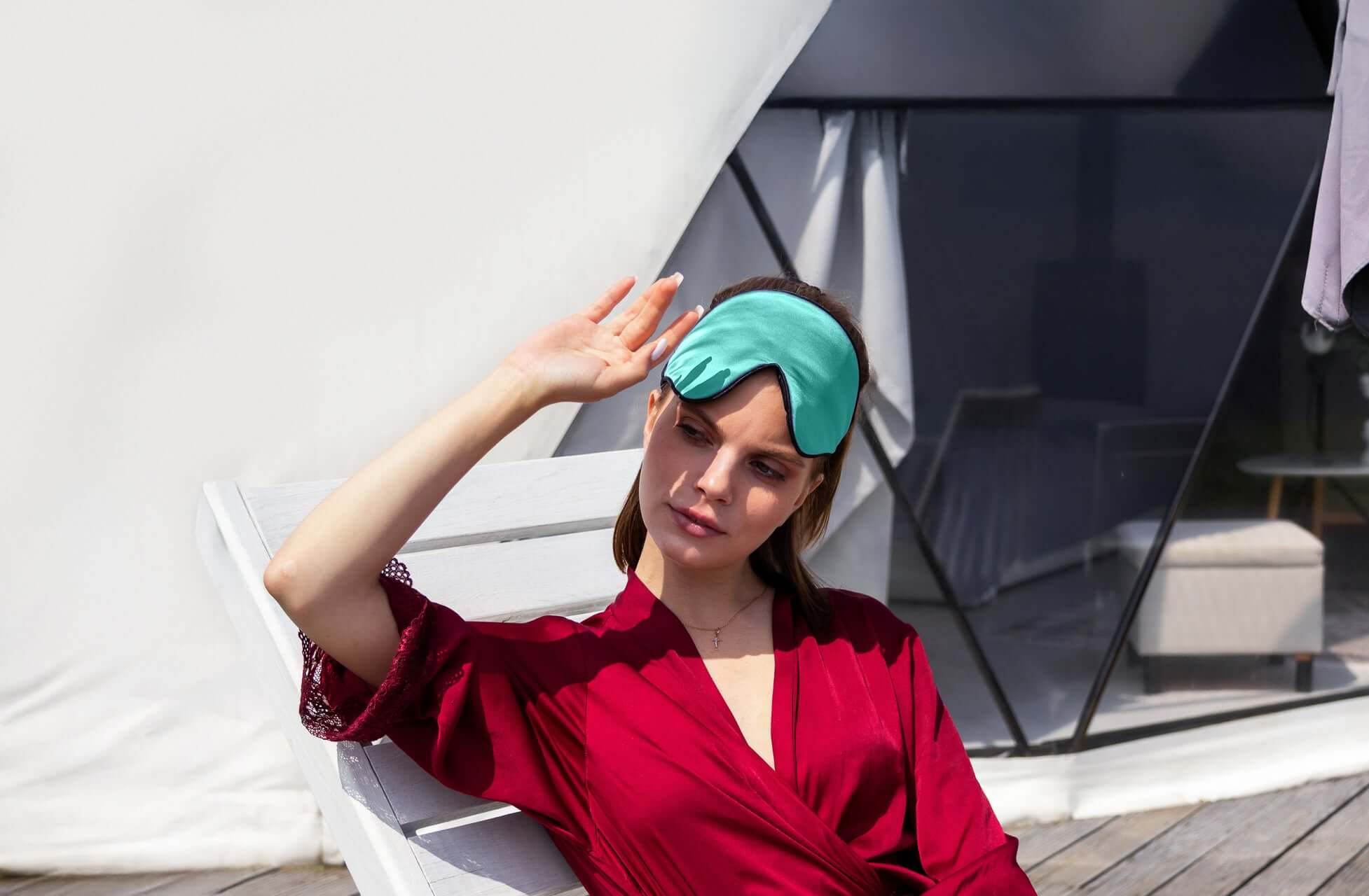 Woman relaxing outdoors with Quietstore 3.0 silk sleep mask, promoting restful sleep and comfort.