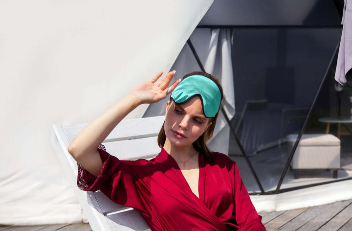 Woman relaxing outdoors with Quietstore 3.0 silk sleep mask, promoting restful sleep and comfort.