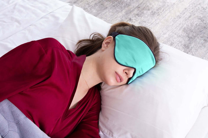 Woman sleeping with Quietstore 3.0 non-slip silk sleep mask on a pillow, promoting restful sleep and comfort.