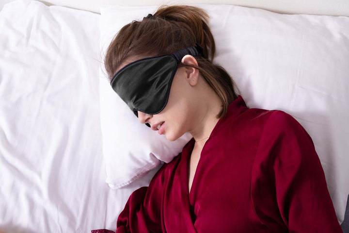 Woman wearing Quietstore 3.0 non-slip silk sleep mask, promoting restful sleep and comfort on a pillow.