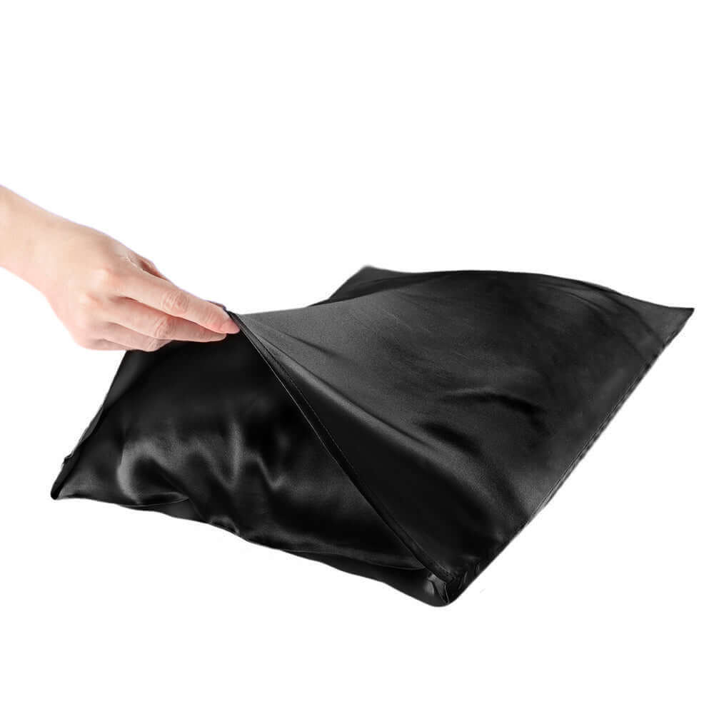 Hand revealing black mulberry silk pillowcase, promoting hair and skin health with moisture retention.