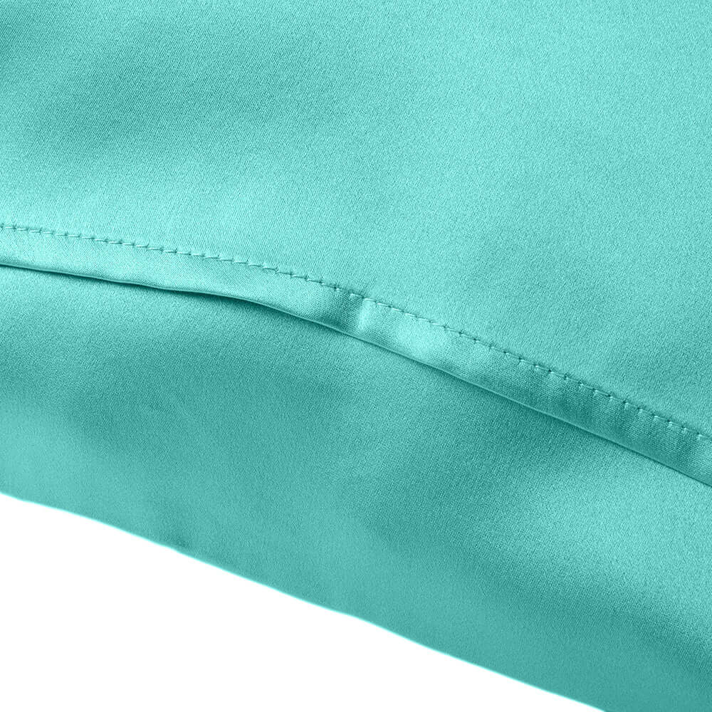 Close-up of a turquoise silk pillowcase showcasing smooth texture and fine stitching details.