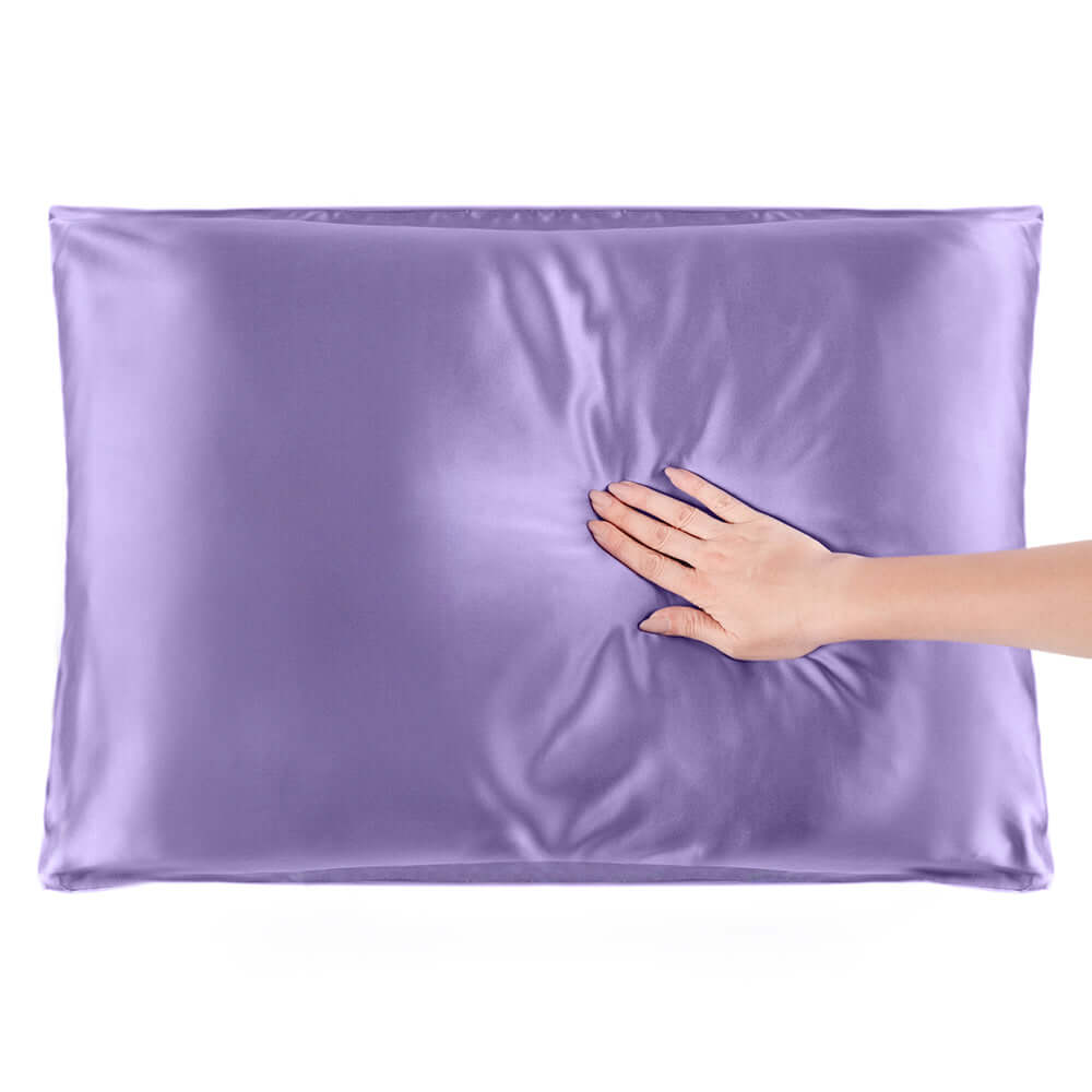 Hand gently pressing a soft mulberry silk pillowcase in lavender color for better hair and skin health.