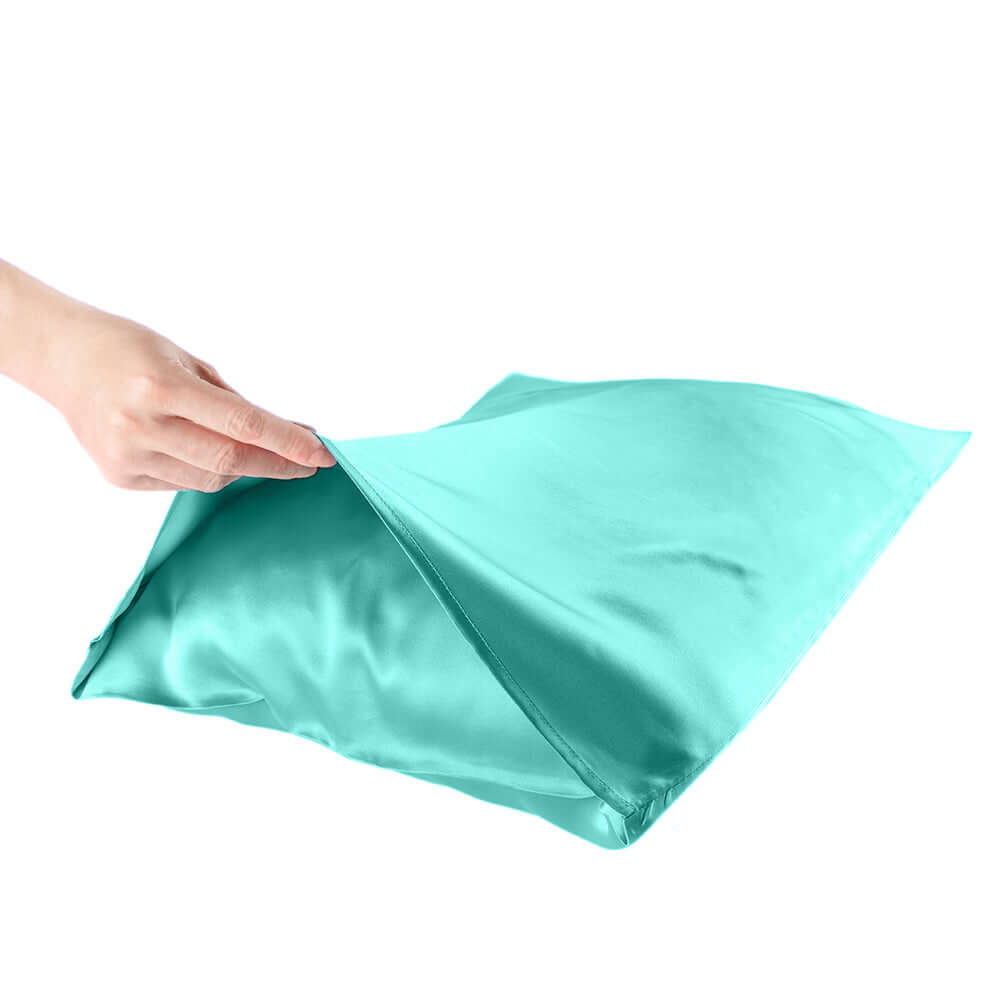 Hand holding a teal silk pillowcase, highlighting its smooth texture for hair and skin care.