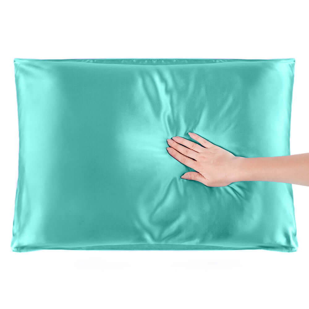 Turquoise mulberry silk pillowcase with a hand resting on it, showcasing its smooth texture and quality.