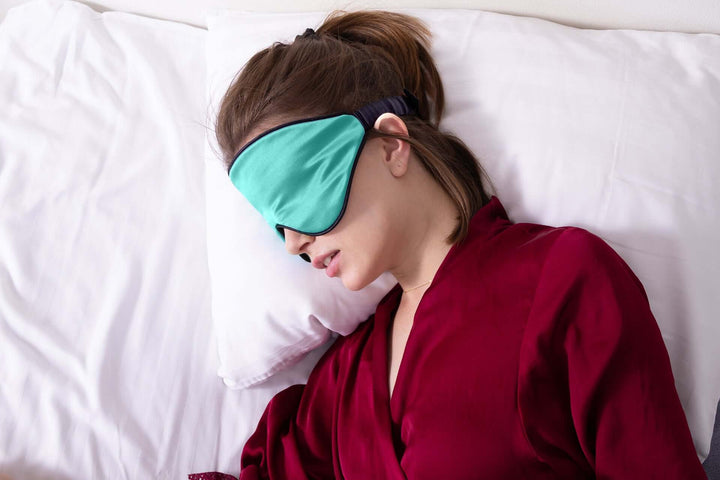 Woman wearing Quietstore 3.0 silk sleep mask for deep, restful sleep with secure non-slip strap.