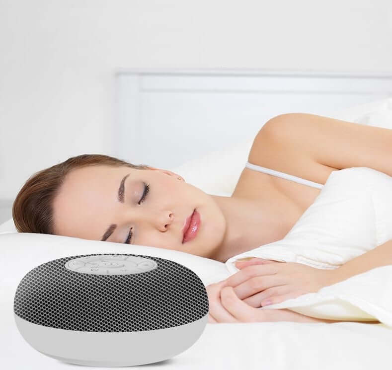 Tuodi white noise sound machine beside a woman sleeping peacefully in bed, promoting restful sleep.